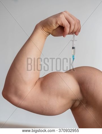 Closeup Of A Male Hand With A Dope Syringe. Cropped Biceps Of A Man. Unrecognizable Bodybuilder Sets