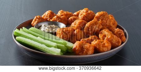 plate of boneless chicken wings with buffalo sauce and celery sticks