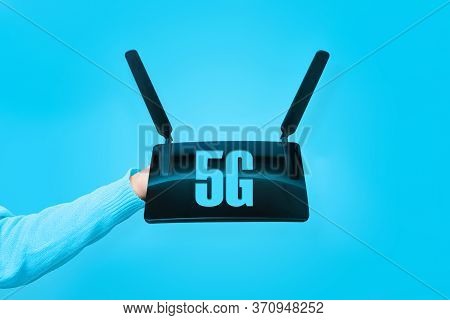 Black Wifi Router On Hand And 5g Inscription Over Blue Background
