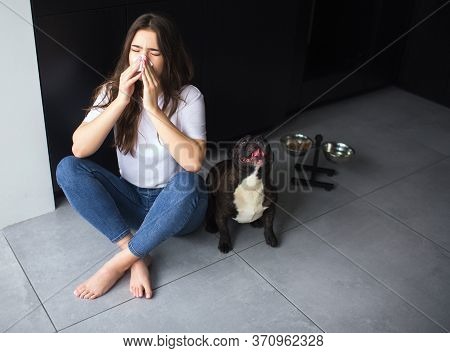 Young Woman In Kitchen During Quarantine. Sit On Floor And Sneeze Into White Tissue. Girl Sick And I