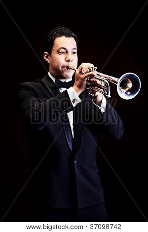 Retrato de um músico tocando a trombeta. Fundo preto.