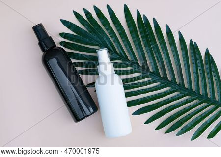 Two Colored Black And White Bottles Onbackground With Green Long Leaf. Natural Organic Eco Cosmetics