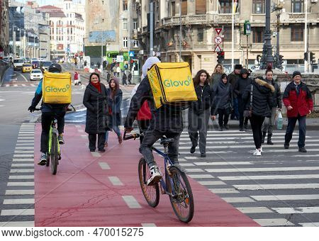 Bucharest, Romania - February 01, 2023: Two Glovo food delivery couriers delivers food in Bucharest, Romania.