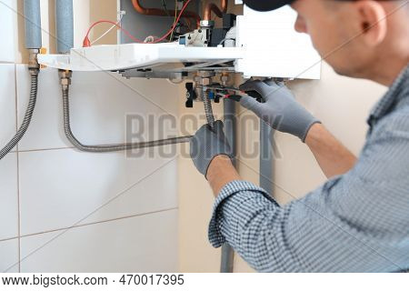 Man Repairing Gas Boiler With Waterpump Plier Indoors, Closeup