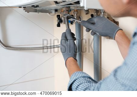 Man Repairing Gas Boiler With Waterpump Plier Indoors, Closeup