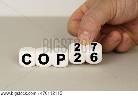 On A Gray Surface Are White Cubes With The Inscription - Cop26 To Cop27. Two Dice In Hand. Technolog