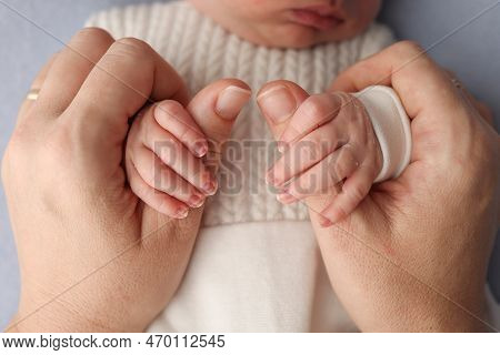 The Newborn Baby Has A Firm Grip On The Parents Finger After Birth. Close-up Little Hand Of Child An