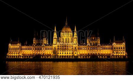 Budapest Parliament Building At Night From Across The Danube River With Reflection In Water. Hungary