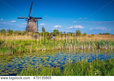 Cute Old Wooden Windmill On The Shore Of The Reedy Water Canal, Kinderdijk Museum, Netherlands, Euro