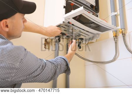 Man Repairing Gas Boiler With Waterpump Plier Indoors, Closeup