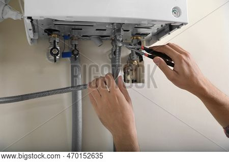 Man Repairing Gas Boiler With Waterpump Plier, Closeup