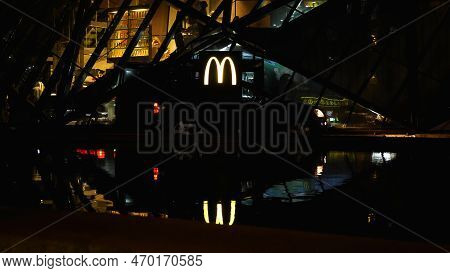 A Car Is Parked Outside Mcdonalds, Picking Up An Order. In The Background, Theres A Glowing Company 