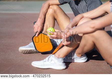Pickleball Game, Relaxing Pickleball Players Couple With Yellow Ball With Paddle Sitting After Game,