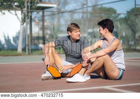 Pickleball Game, Relaxing Pickleball Players Couple With Yellow Ball With Paddle Sitting After Game,
