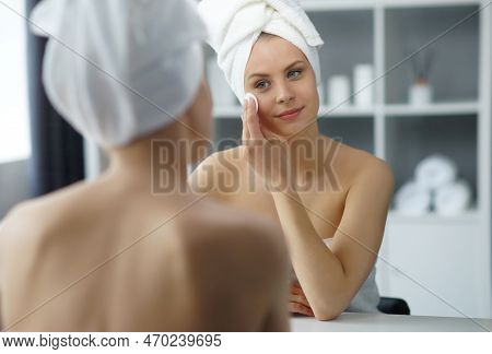 Young Woman Sits In The Bathroom In Front Of The Makeup Mirror And Does Cosmetic Procedures. Beautif