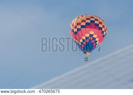 Hot Air Balloon In Flight. One Hot Air Ballooning Flying In The Sky In Switzerland. Chateau D'oex, V