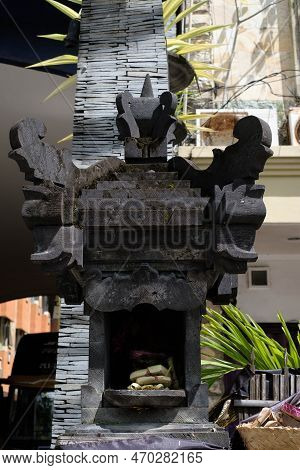 A Beautifully Arranged Canang Sari Offering Rests In A Traditional Balinese Spirit House, Surrounded