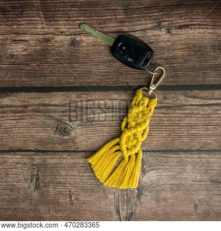 Top View Of The Handmade Macrame Key Chain Hanging On The Car Key Isolated On The Wood Background.