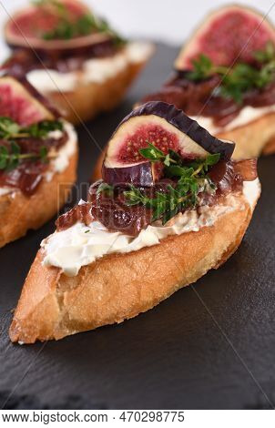 Canape Or Crostini With Toasted Baguette, Cream Cheese, Onion Jam, Figs And Fresh Thyme On A Slate B