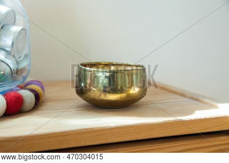 Gold Candle And Tinsha On A Wood Table.