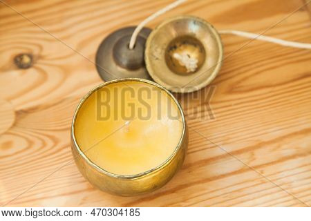 Gold Candle And Tinsha On A Wood Table.