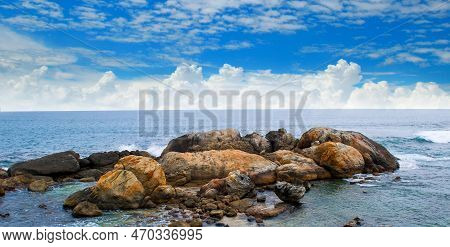 Ocean Waves Crashing On Coastal Rocks On A Sunny Summer Day With Blue Clear Skies And A Scenic Tropi