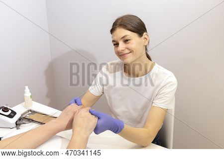 Smiling Caucasian Manicure Technician, Nail Stylist In Gloves Holds Hands Of White Client, Preparing