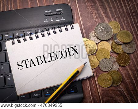Notebook And Coins On A Wooden Background With The Word Stablecoin.
