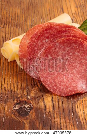 Feta und Ementhal Käse mit Salami und Gurken auf einer Holzplatte