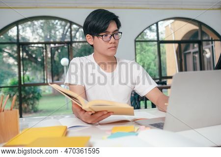 Young Asian University Student Is Reading A Book For Exams. The College Student Self Learning And St
