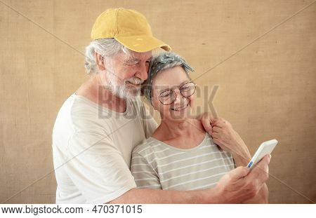 Beautiful Smiling Senior Couple Hugging Looking Together At Phone. Bearded White Haired Elderly Man 