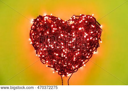Tangled Wires Of A Garland With Red Light Bulbs Folded In The Shape Of A Heart On A Lemon Background