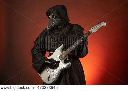 A Man In A Plague Doctor Costume Plays The Guitar Emotionally On A Red Background