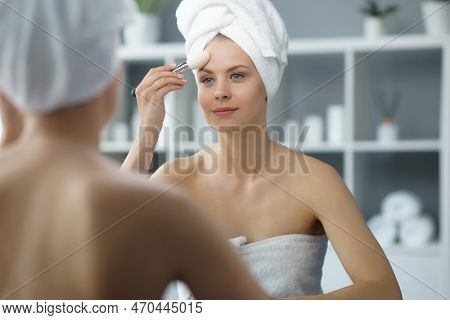 Young Woman Sits In The Bathroom In Front Of The Makeup Mirror And Does Cosmetic Procedures. Beautif