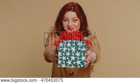 Positive Smiling Redhead Woman Presenting Birthday Gift Box Stretches Out Hands, Offer Wrapped Prese
