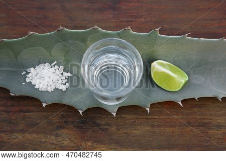 Mexican Tequila Shot, Salt, Lime Slice And Green Leaf On Wooden Table, Top View. Drink Made Of Agava