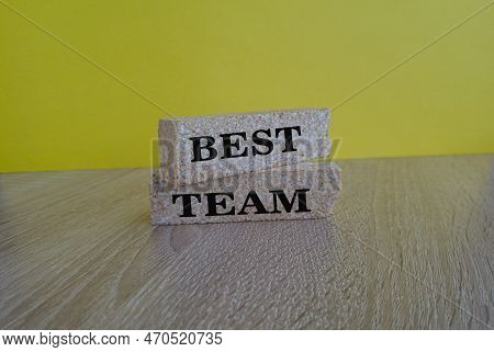 Words 'best Team' Symbol On Brick  Blocks    On  A Wooden Table On A Beautiful Yellow  Background. B
