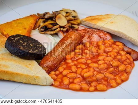 White Board With Full English Breakfast With Bacon, Fried Egg, Beans, Tomato, Roasted Sausage, Black