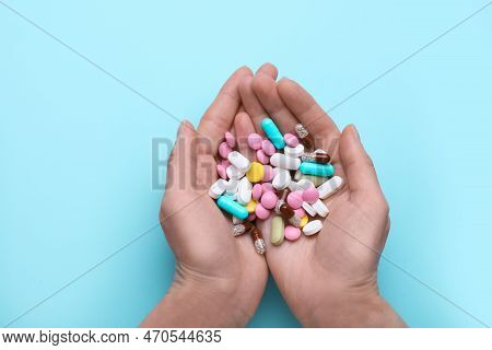 Woman Holding Colorful Antidepressants On Light Blue Background, Top View
