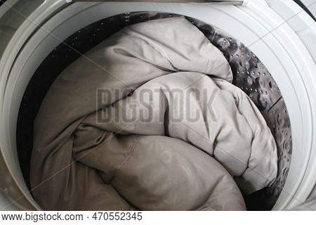 Roll Up The Duvet And Put It In The Washing Machine.for The Presentation Of The Washing Machine.