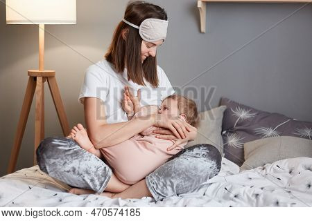Symbol Mother Love And Happiness. Image Of Young Mother Holding Her Infant Child And Nursing, Posing