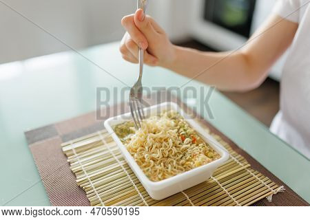 A Shot Of Someone Enjoying A Quick And Unhealthy Meal Of Instant Noodles, With The Focus On The Fork