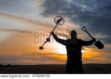 A Happy Treasure Hunter With A Metal Detector On The Background Of A Beautiful Sunset
