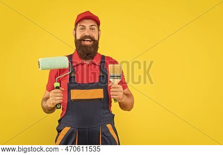 Amazed Bearded Man Housepainter In Work Clothes Hold Paint Roller And Brush On Yellow Background
