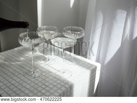 Champagne Pourig Into Glasses On A Light Table Surface Reflecting Soft Sunshine Rayson. Sparkling Wi