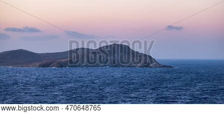 Rocky Island On Mediterranean Sea. Rinia Near Mikonos, Greece, Europe. Nature Background. Sunrise Sk