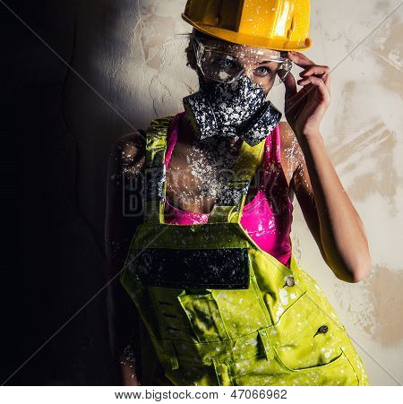 Coverall, kask ve solunum eski duvardan poz giyen kadın inşaat işçisi