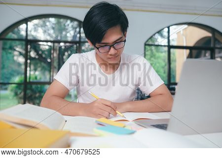 Young Asian University Student Is Reading A Book For Exams. The College Student Self Learning And St