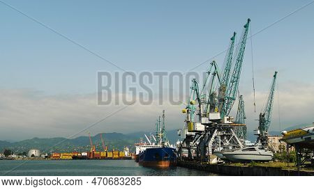 A Commercial Port With Dockside Cranes. A Ship For Lng, Containers And Dry Cargo. With A Mountain In