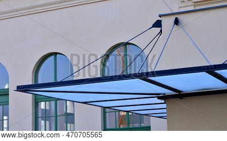Glass Shelter By A Beige Historical Building. Attached To The Facade Of The Wall In A Metal Frame Su